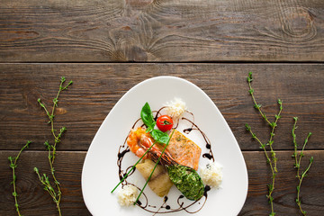 Seafood variety flat lay copyspace. Top view on white triangle plate with stuffed mussel, shrimp, red and white grilled fish with free space for advertisement. Plate with seafood on wood, void