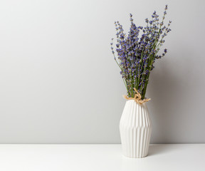 Bunch of lavender in a vase on a white table with light from one side to create a small shadow
