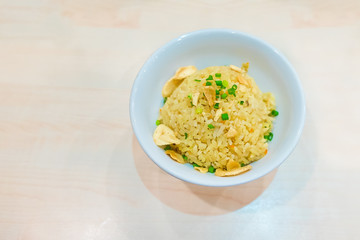 Thai garlic fried rice with vegetable on top in white bowl, on w