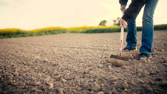 Farmer Using Hoe On Dirt At Farm