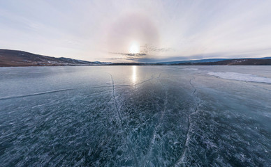 Blue ice of Lake Baikal covered with cracks, cloudy weather at s