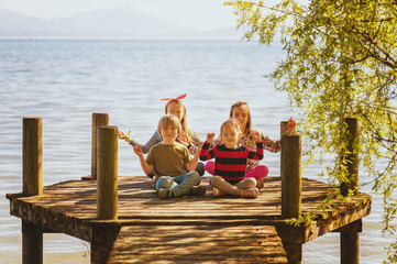 4 kids playing by the lake, four children meditating on the pier, toned image