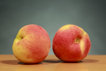 Two red apricots on wooden surface and green background