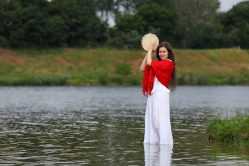 Young brunette woman playing tambourine at a lake