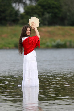 Young Brunette Woman Playing Tambourine At A Lake