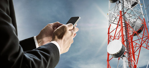 Businessman using mobile phone, with satellite dish telecom network on telecommunication tower on...