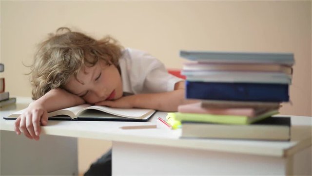 A child of primary school age do homework. The boy does his homework at his desk at home.pupil has been bored on the lesson