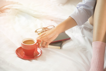 Beautiful woman drinking coffee on bed, in the morning.