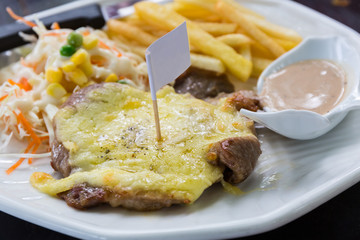 Grill pork steak under white sauce, French Fries (potato chips).