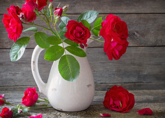 Red rose in vase on wooden background