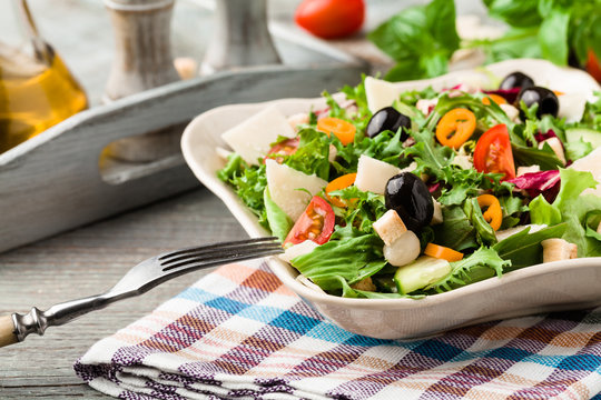 Italian salad with fresh vegetables with black olives and Parmes