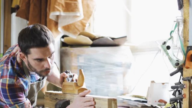 carpenter working with plane and wood at workshop