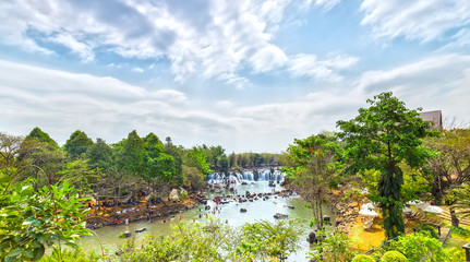 Giang Dien Waterfall above with water pouring down billowing white, surrounded by a forest covered attract many tourists to the resort, above the beautiful cloudy sky sunny day fresh welcome freshness