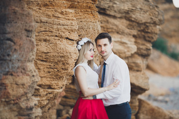 Romantic loving couple walking on the beach with rocks and stones