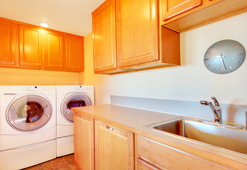 Laundry room with modern appliances and light tone cabinets.