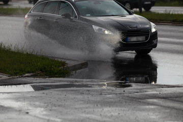 Car splashing water on the street after heavy rain