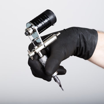 close-up of Tattooist hands in black gloves with tattoo machine