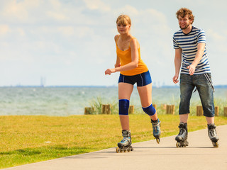 Obraz premium Young couple on roller skates riding outdoors