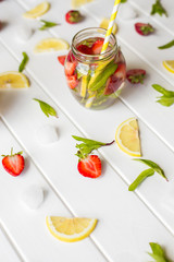 Refreshing summer drink with mint inglasses and strawberry on the wooden white table