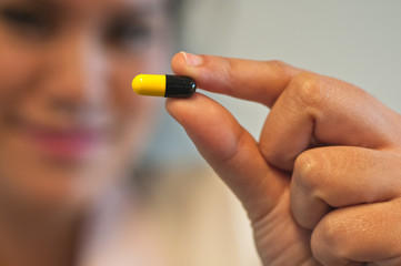 Medicine capsule is held by woman fingers
