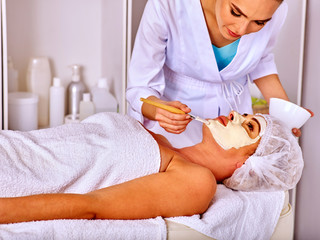 Obraz na płótnie Canvas Woman middle-aged lie on massage table take facial and neck clay mask in spa salon.