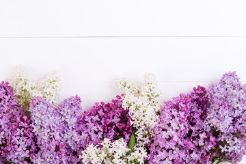 The purple and white lilac flowers on a white wooden table
