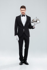 Handsome young man waiter holding tray and lid