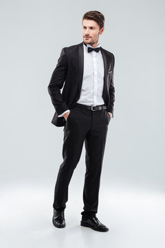 Full length of confident attractive young man in tuxedo