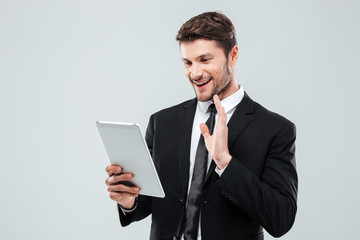 Smiling young businessman using tablet and making video conference