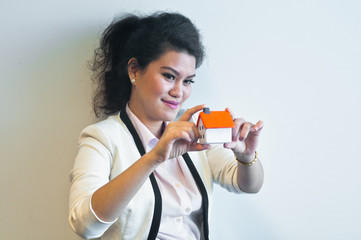 Woman looks and holds a house model on white background