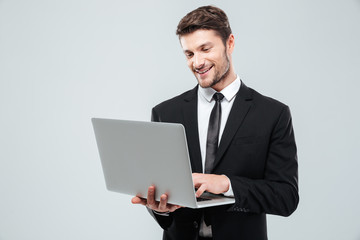 Cheerful young businessman smiling and using laptop