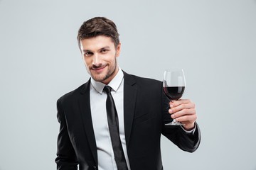 Smiling young businessman holding glass of red wine