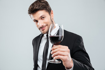 Handsome young man smiling and holding glass of red wine