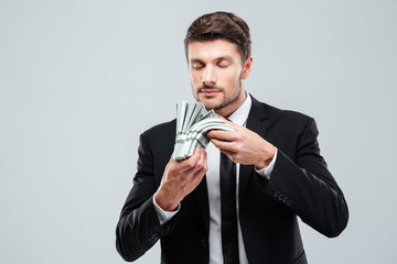 Handsome young businessman holding and smelling money