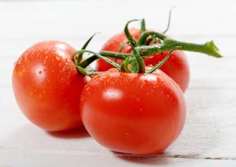 Three tomatoes on white wooden table