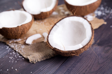 Fototapeta na wymiar Coconut halves with shell on a dark wooden table