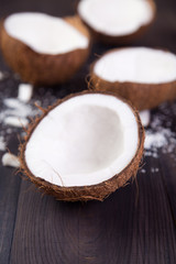 Fototapeta na wymiar Coconut halves with shell on a dark wooden background
