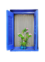 Wooden window with open window blind painted in blue, lace curtain and a flower pot on a white wall. Greece, september 2014