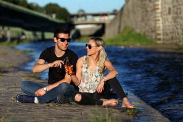 Attractive young couple having a drink at a river