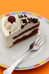Schwarzwälder Kirschtorte, Torte auf einem Teller auf orangefarbenem Untergrund