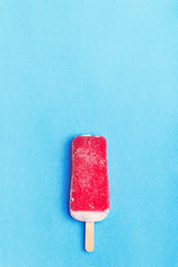 Single homemade strawberry popsicle on a blue background. Top view with copyspace