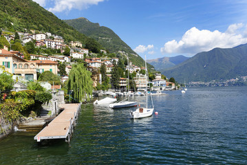 Fototapeta na wymiar A beautiful day on lake Como in the romantic town Moltrasio. Villas, sailboat and jetty. Italy, Europe, sept. 2015