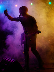 Silhouette of guitar player on stage.