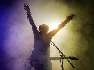 Silhouette of guitar player on stage.