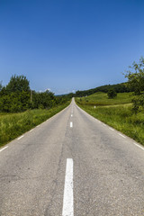 Empty asphalt road in countryside, bend of road, field in the ba