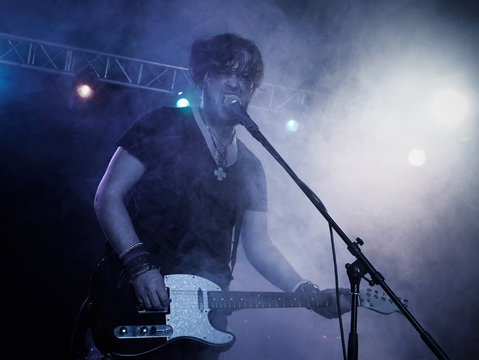 Silhouette of guitar player on stage.