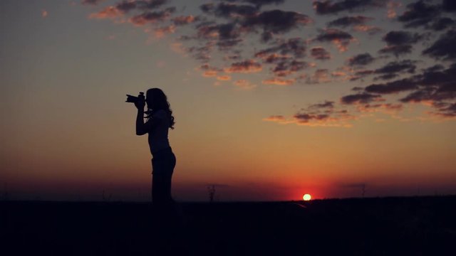 silhouette of woman take photo on sunset background