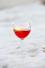 glass of rose wine in the sea foam of the surf. sunshine in a glass. Natural sea summer background. Recreation
