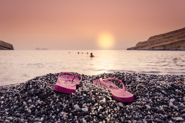 Sunset with woman's  sandals on the beach 