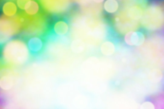 colorful bright bokeh background in shades of blue, green, yellow and purple with a bright highlight at the bottom